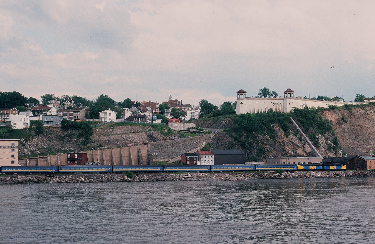 The 1984 view of Levis, P.Q. from the Terrasse Dufferin ( Promenade du Gouverneurs) in front of the Chateau Frontenac.


The Via Rail special, destined for Montreal, powered by a pair of (Quebec built) FPA-4's, is at the south shore Gare du Levis platform (mile 114.8 Montmagny Sub.).  Station building is to the left out of the image. The Gare du Levis was within a short walk of the Ferry Terminal with frequent service to Lower Quebec City.


The reason for the special: 1984 marked the 350th anniversary of the founding of Quebec City. The Federal Government expended considerable monies to celebrate by way of a week long festival including the 1984 Tall Ships regatta. 
 

Perhaps the Gare du Levis was utilizied due to road and related construction near the Gare du Palais closing that station to rail traffic for several years. Throughout the mid eighties all Quebec City trains terminated / originated at Ste-Foy, 12.3 rail miles west of the Gare du Palais.


Levis, P.Q. was a station stop for the daily trains #14 and #15  Ocean ( 22:28 and 04:57 ) as well as the daily trains #16 and #17  Chaleur  ( 02:57 and 10:19 ) with the  24 hour Ferry connection to lower Quebec City, a nine minute ride from the Levis dock. 


Today this section of the Montmagny Subdivision is gone, lifted from St-Charles (mile 101.3) to east of  Charny ( mile 122.9) and the Ocean now stops on the north shore at Ste-Foy.


June 29, 1984 Kodachrome by S.Danko


What's interesting:


The 1984 Tall Ship regatta included a tall ship full fleet all colour sail past ( tall sail ships from Argentina, Britain, France, Germany ( East and West - separate countries ), Poland,  U.S.A., U.S.S.R. (the Soviet country), Venezula and more were invited and attended), hence the Via special.  


During this time the Quebec Separatist movement (Rene Levesque of the P.Q. was the Quebec Premier ) was quite strong and the Federal Government was doing whatever possible to boost Federalism. Via Rail was included as part of the festival as an access partner and the CNR ( owned by the Federal Government) and CP Rail also contributed operational assistance for the National Museum owned ex CPR #1201 as part of the transportation celebration.
 

   see      Charny  
 

And yes that is a pontoon equipped helicopter above the lead FPA-4.


The Ste-Foy / Gare du Palais shuttle initiated during the construction that closed the Gare du Palais to rail traffic (during the mid-eighties) continues to operate today.


More sights on the way to Quebec City:
 

         Monk  
 

         Drummondville  
 

         Baie St Paul  
 

sdfourty