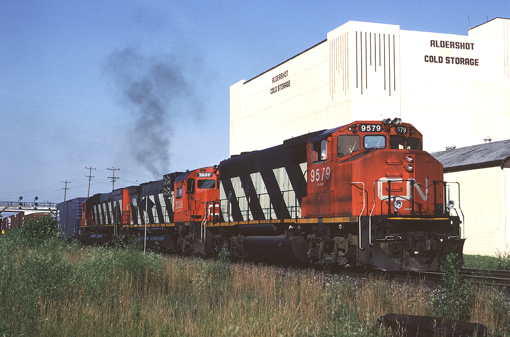 Canadian National GP40-2W 9579 (with a pair of MLWs trailing) leads Toronto - Fort Erie train #433 past the Aldershot Cold Storage plant at the west end of Aldershot. They are likely making a lift from Aldershot yard as eastbound trains would setout Niagara-bound traffic for pickup by #433.