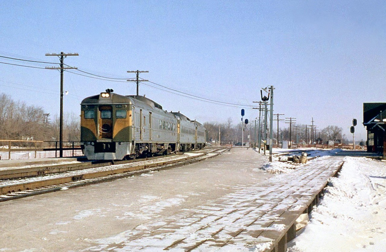 Westbound Canadian National Railiners (CN's term for Budd RDC cars) pass Port Credit station, on a "shoe fly" built during construction of the underpass for Hurontario Street (Highway 10) in the Winter of 1962. The station, along with the Oakville Subdivision's normal right-of-way alignment, platforms and signals can be seen on the right, with construction going on in the background where the line intersected the highway. Temporary signals and platforms were build along the shoe fly for passengers to embark/disembark at the station.  More at Port Credit: CN 2602 crossing the Credit River bridge: http://www.railpictures.ca/?attachment_id=14124 CN 4-8-4 "Northern" 6184 in 1958: http://www.railpictures.ca/?attachment_id=15317  [Editor's note: You can see the Port Credit shoe fly construction from 1962/1963 in the City of Toronto's online 1963 aerial imagery *here*.]