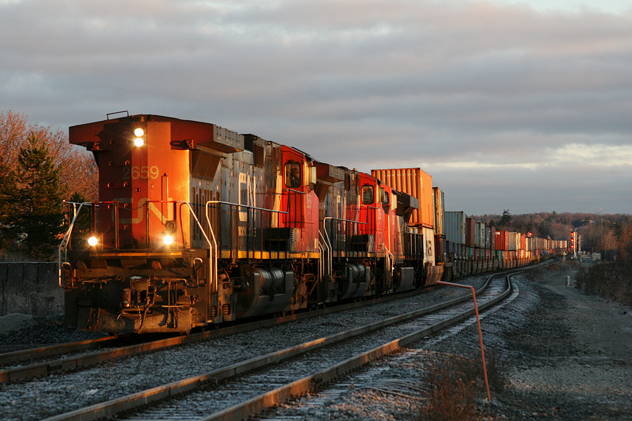 CN Q 11251 24 crosses from the east track to the west track at Elgin after meeting M 30131 29 on the double track at Quaker.  This 9932 foot long intermodal from the west coast is powered by CN 2659, IC 2725, CN 2317 with CN 2525 shoving on the tail end.  The 2659 has been leading the track backwards since the Redditt Sub, where CN 2317 suffered a crank case failure, leaving the train limping along at a 0.4HPT and with the clock ticking towards the battery power running out; effectively leaving the unit without heat, lights and control over the DP unit which is also the SBU.  CN 2659 and IC 2725 were pulled off X 31731 26 online to rescue the train and clear the single track mainline.  Without an opportunity to wye the power across the north, we see 112 in its unusual configuration approximately 1000 miles later as the sun rises over the Bala Sub at 0749.