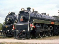 <b>Big steam at St. Thomas:</b> Canadian National 5700 and Reading 2100 pose next to each other on an Iron Horse day outside the former Michigan Central shop building at the Elgin County Railway Museum.<br><br>CNR 5700 is a K5a-class 4-6-4 "Hudson" built for CN in November of 1930 by MLW. While CP accumulated 65 Hudson type steam locomotives, CN only rostered 5: 5700-5704. They were used in passenger service out of Spadina Roundhouse in downtown Toronto until eventual retirement at the end of the steam era. When retired, two were donated to museums: 5702 to the Canadian Railway Museum/Exporail in Delson QC, and 5703 (as 5700) to the National Museum of Science and Technology (NMST). CN had the intent to preserve the "class" unit of the group like Northerns 6200 and 6400 were, but the original 5700 was inadvertently scrapped, so 5703 was renumbered as 5700 when donated to the NMST in November 1961. In 1988, "5700" went to the Elgin County Railway Museum where it resides today.<br><br>Reading 2100 is a Reading-built 4-8-4 Northern, at the time privately owned by Tom Payne and stored at ECRM with plans to put it into excursion service. It has since been sent back to the US, more details on 2100 can be found on the photo of it <a href="http://www.railpictures.ca/?attachment_id=21299"><b>*here*</b></a>.<br><br>For a photo of sister CNR Hudson 5702 in passenger service: <a href="http://www.railpictures.ca/?attachment_id=14106"><b>http://www.railpictures.ca/?attachment_id=14106</b></a>