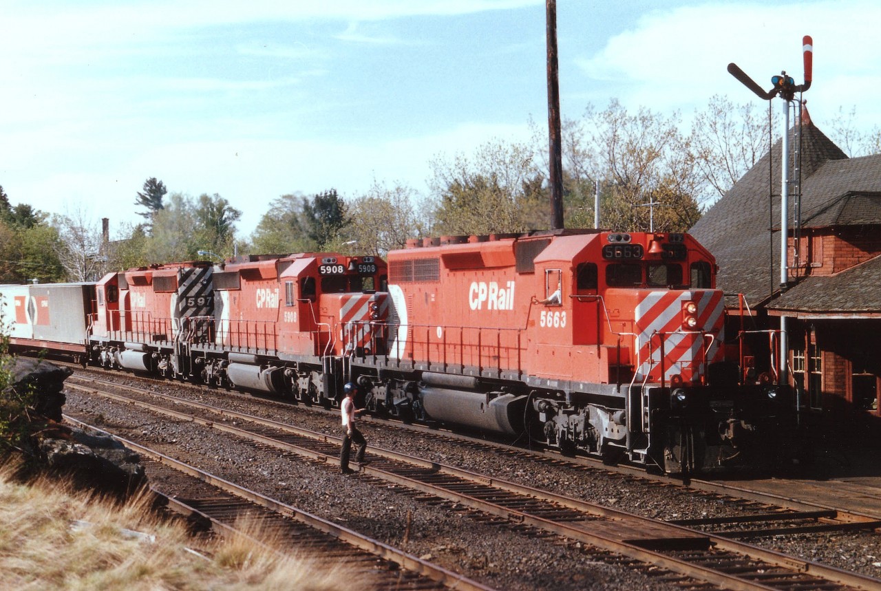 Greetings exchanged between engineer and one of the local maintenance guys as CP 5663 West (I always refer to them as "North" thru here)slows up as flimies are about to be handed up as the caboose passes. Power on this train is CP 5663, 5908 and 5974. One of the things I loved about hanging out at the station was the freedom to cross the tracks at will. And for morning northbounds, this was the very best place for sun angle as the northbounds came off the trestle turning abruptly eastward for a half mile before the tracks turned north again.