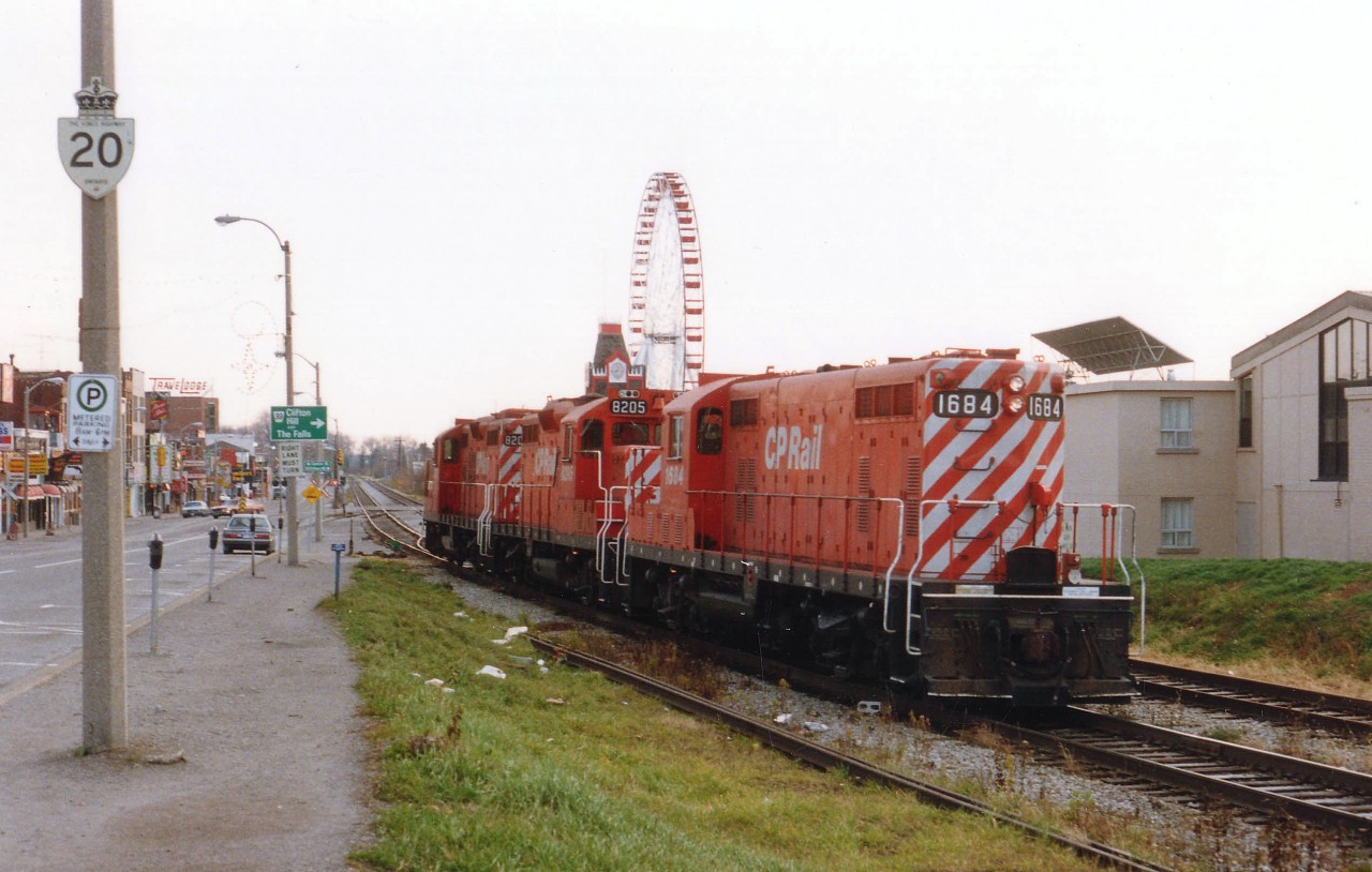 This image of a CP power move thru the downtown tourist area of Niagara Falls shows much of the double track line that used to run thru the area. Also barely seen is the spur that crossed over the former Hwy 20 (Ferry St) to a plant over on Stanley Av. if my memory serves me correctly. Nabisco?? Whatever. The track had been out of service for quite some time by 1988. Note how quiet the streets are after all tourists have returned home after their summer fleecing. Power shown is CP 1684 (the old TH&B 74!!), 8205 and 8207.