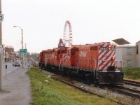 This image of a CP power move thru the downtown tourist area of Niagara Falls shows much of the double track line that used to run thru the area. Also barely seen is the spur that crossed over the former Hwy 20 (Ferry St) to a plant over on Stanley Av. if my memory serves me correctly. Nabisco?? Whatever. The track had been out of service for quite some time by 1988. Note how quiet the streets are after all tourists have returned home after their summer fleecing. Power shown is CP 1684 (the old TH&B 74!!), 8205 and 8207.