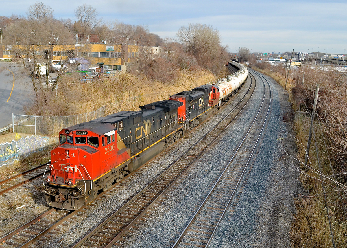 CN's first Dash9 leading the TankTrain. CN 2500 (CN's first Dash9) and CN 8877 head west with CN 785 just as the sun pops out. This unit train transports gas from the refinery in St-Romuald, Quebec to the Ultramar terminal in Maitland, Ontario.