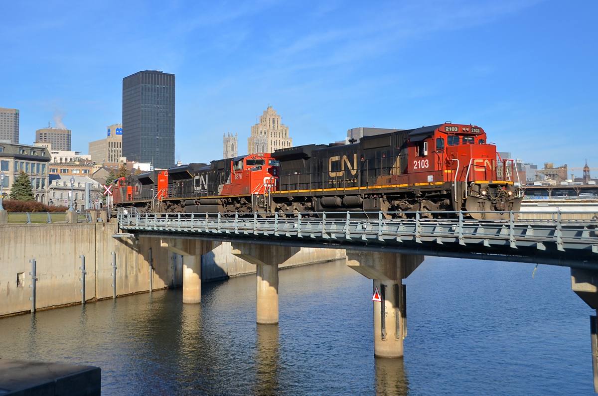 A standard cab leader for once. Standard cab C40-8 CN 2103 is leading CN 149, a nice change from the widecab ES44AC's which are now power for this train most of the time. Here CN 149 crosses the Lachine canal with high priority intermodal from the harbour. Trailing is CN 8876 & CN 8855.