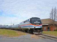 <b>Heritage Amtrak unit leading.</b> Heritage unit AMTK 822 leads the southbound Adirondack (AMTK 68, AMTK 694 while on CN tracks) around a curve in St-Jean-sur-Richelieu. Behind it is the ex-Grand Trunk station.
