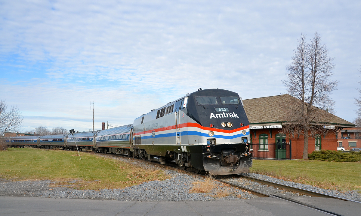 Heritage Amtrak unit leading. Heritage unit AMTK 822 leads the southbound Adirondack (AMTK 68, AMTK 694 while on CN tracks) around a curve in St-Jean-sur-Richelieu. Behind it is the ex-Grand Trunk station.
