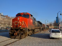 <b>Past Port of Montreal security.</b> CN 149 has just left Port of Montreal trackage and is on the CN Wharf Spur as it passes a crossing that is flagged by a Port of Montreal employee. The Port of Montreal security flags the many crossings in this busy and tourist-intensive area. Lashup is CN 2598, IC 1001 & CN 2631.