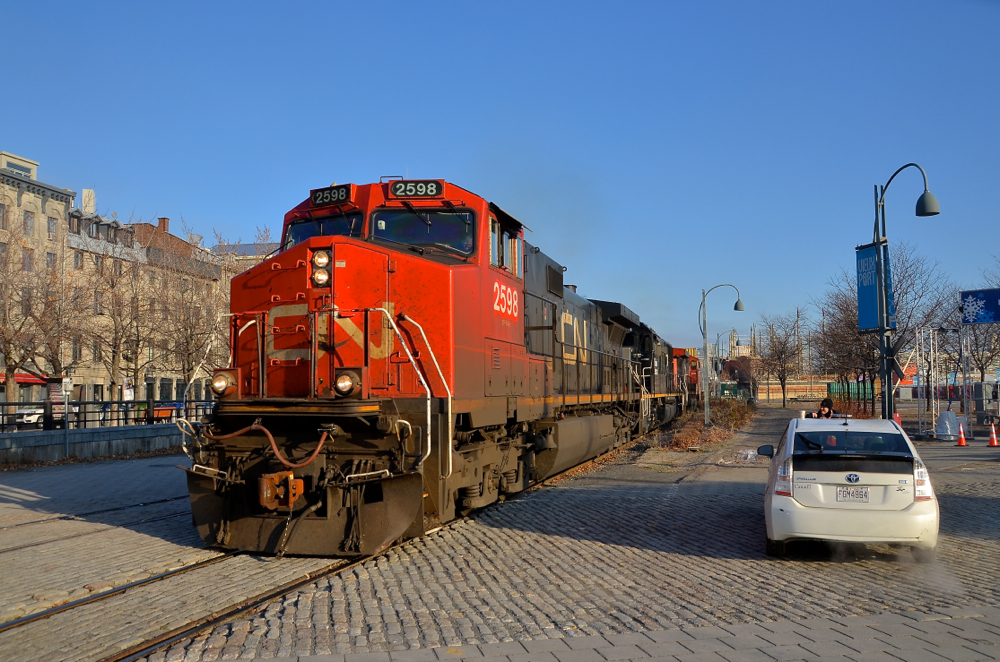 Past Port of Montreal security. CN 149 has just left Port of Montreal trackage and is on the CN Wharf Spur as it passes a crossing that is flagged by a Port of Montreal employee. The Port of Montreal security flags the many crossings in this busy and tourist-intensive area. Lashup is CN 2598, IC 1001 & CN 2631.