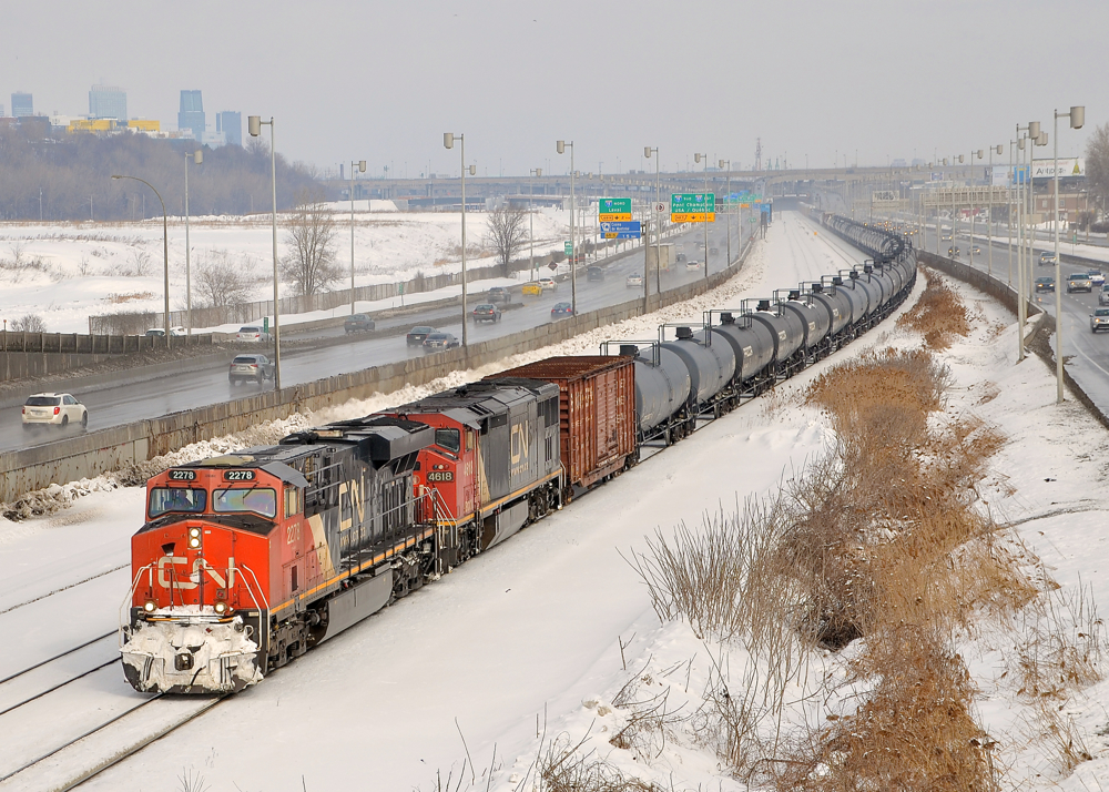 Almost like a unit train. CN 2278 & repainted BCOL 4618 lead CN 305 towards Turcot West where it will get a new crew. In the background at left is downtown Montreal and at right is the Turcot highway interchange. With so many tank cars at the head end, this looks like it could be a unit oil train.