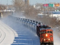 <b>Dashing through the snow with a cowl leader.</b> CN 2443 and a CN Dash9 are roaring through Montreal West with CN 711, kicking up snow as they go.