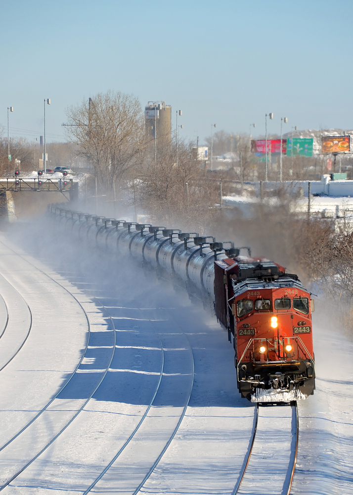Dashing through the snow with a cowl leader. CN 2443 and a CN Dash9 are roaring through Montreal West with CN 711, kicking up snow as they go.