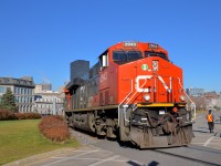 <b>Flagging the crossing.</b> CN 2943 is in charge of CN 149 as it rounds a curve in the Port of Montreal, with CN 3023 trailing. In a few seconds the head end will cross the Lachine canal on a sunny fall morning. At right is a Port of Montreal employee flagging this crossing.