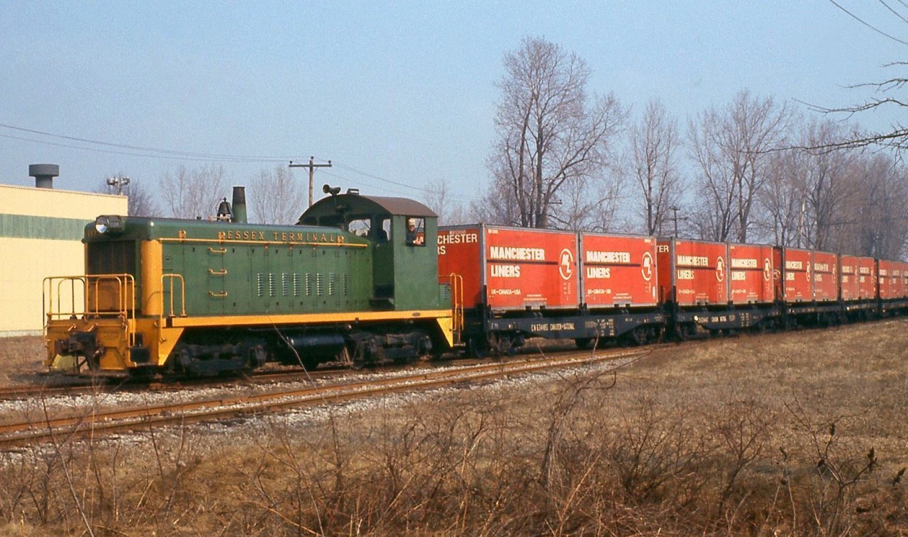 Essex Terminal SW8 104 heads south from Windsor, with some early containers: Manchester Liners ("UK-Canada-USA") 20' containers loaded on 40' CN flatcars.Note: geotagged location not exact.
