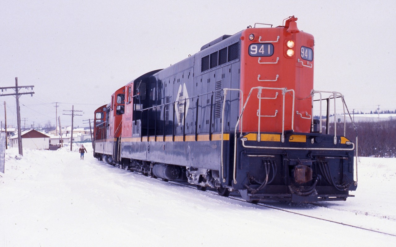 CLASSIC 1980's - Leading unit NF210 #941 of Terra Transport Mixed Extra 941 West is paused Grand Falls during Christmas week of 1987 so the trainman can attend to the switch.The 1200 horsepower unit with a CN Class of GR-12-x and built by GMD of London Ontario, was one of 9 in the final order shipped to Newfoundland in 1960. Its new paint and the excellent maintenance carried out by the shop crews in St. John's belies the fact that this particular unit was 27 years old!Although suspected but not confirmed until a few months later, the former Newfoundland Railway was living on borrowed time and it would be the last Christmas week that Grand Falls or any other town on the Island would ever see train service again.