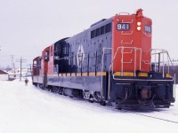 CLASSIC 1980's - Leading unit NF210 #941 of Terra Transport Mixed Extra 941 West is paused at Grand Falls during Christmas week of 1987 so the trainman can attend to the switch.The 1200 horsepower unit with a CN Class of GR-12-x and built by GMD of London Ontario, was one of 9 in the final order shipped to Newfoundland in 1960. Its new paint and the excellent maintenance carried out by the shop crews in St. John's belies the fact that this particular unit was 27 years old!Although suspected but not confirmed until a few months later, the former Newfoundland Railway was living on borrowed time and it would be the last Christmas week that Grand Falls or any other town on the Island would ever see train service again.