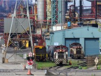 <b>In the industrial heartland of Hamilton</b> a pair of consecutive EMD SW8's Dofasco 411 and 412 sit side by side at the railway's main shop while a transportation dept employee has lunch on the 'grass'. 412 has a Bottle train  and this is a very rare sight - the bottle trains work deep in the plant and are rarely visible from public property. 411 is at the shop proper. To the left of the bottle train is NEW bottle car 625 recently delivered after heading for refurbishment. As of 2014, there are six locomotives assigned to Hamilton, one converted to a Genset (#418 in Arcelor-Mittal Orange), Four EMD's remain (411, 412, 414, 416) and one is being converted (410) which means the SW8's days are certainly numbered. <br>As alluded, this  photo was taken from Public property. 