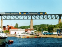 High over the mouth of the Seguin River, VIA 6525, 6653 and 6519 hustle the Toronto section of the "Canadian" over the Parry Sound trestle. What a great view from that baggage car!! Georgian Bay water level looks extraordinary high compared to what I usually witnessed there. Very satisfying image; so went for ice cream at the dock after the train cleared. Lead unit later became AC 1754, trailing unit was retired and the middle unit, 6653, was former CP 1905, also retired by 1990. Note some of the old CP Red beginning to bleed thru.