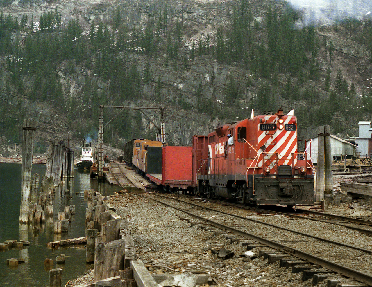 GP9 8821 loads the barge for Rosebery and the isolated Kaslo Subdivision. The modified(For high water) 8821 and crew will board the barge to continue the run to Nakusp. Tug "Iris G" is operated by a contractor.
