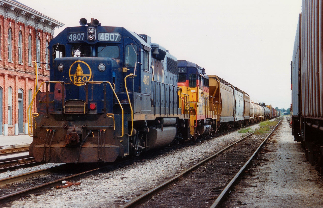 Late afternoon view of B&O 4807 and C&O 3012 west, stopped in front of that huge landmark Canada Southern station in St. Thomas. Only the end is visible but this building is 354 ft long!! Nothing happening here any more, the CASO track has long been pulled up in the 29 years since this photo was taken.