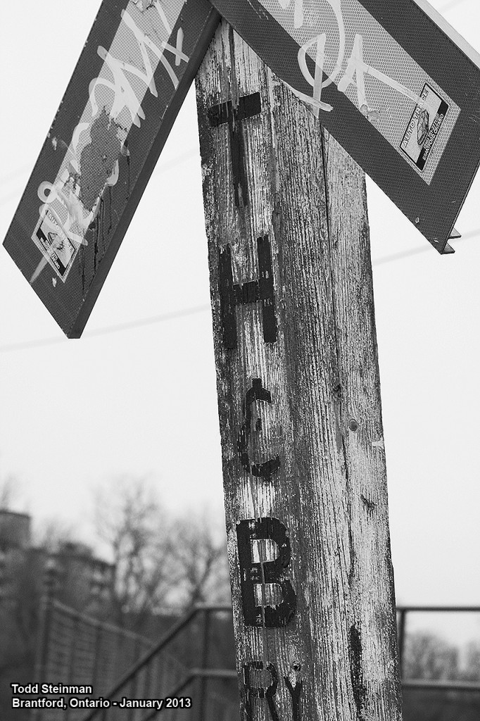 FREE ADVERTISING?  The Toronto, Hamilton and Buffalo Railway Co. was always in the shadow of what is nowadays the two most powerful railroad companies - that of the Canadian National and the Canadian Pacific. Although CP did end up purchasing the TH&B in time,  it all came to a crashing halt in the mid-80's with a devastating landslide after a major rainstorm. It washed away the grade coming down into Brantford on the Waterford Subdivision, thus only today there is a small section of trackage still in place. It is used to serve a couple of industries...and here, beside Earl Haig Park a remnant from the good old days of railroading remains. Although the crossing signs have changed this post still stands, proudly symbolizing an era of railroading that has changed drastically in the last 60 years.