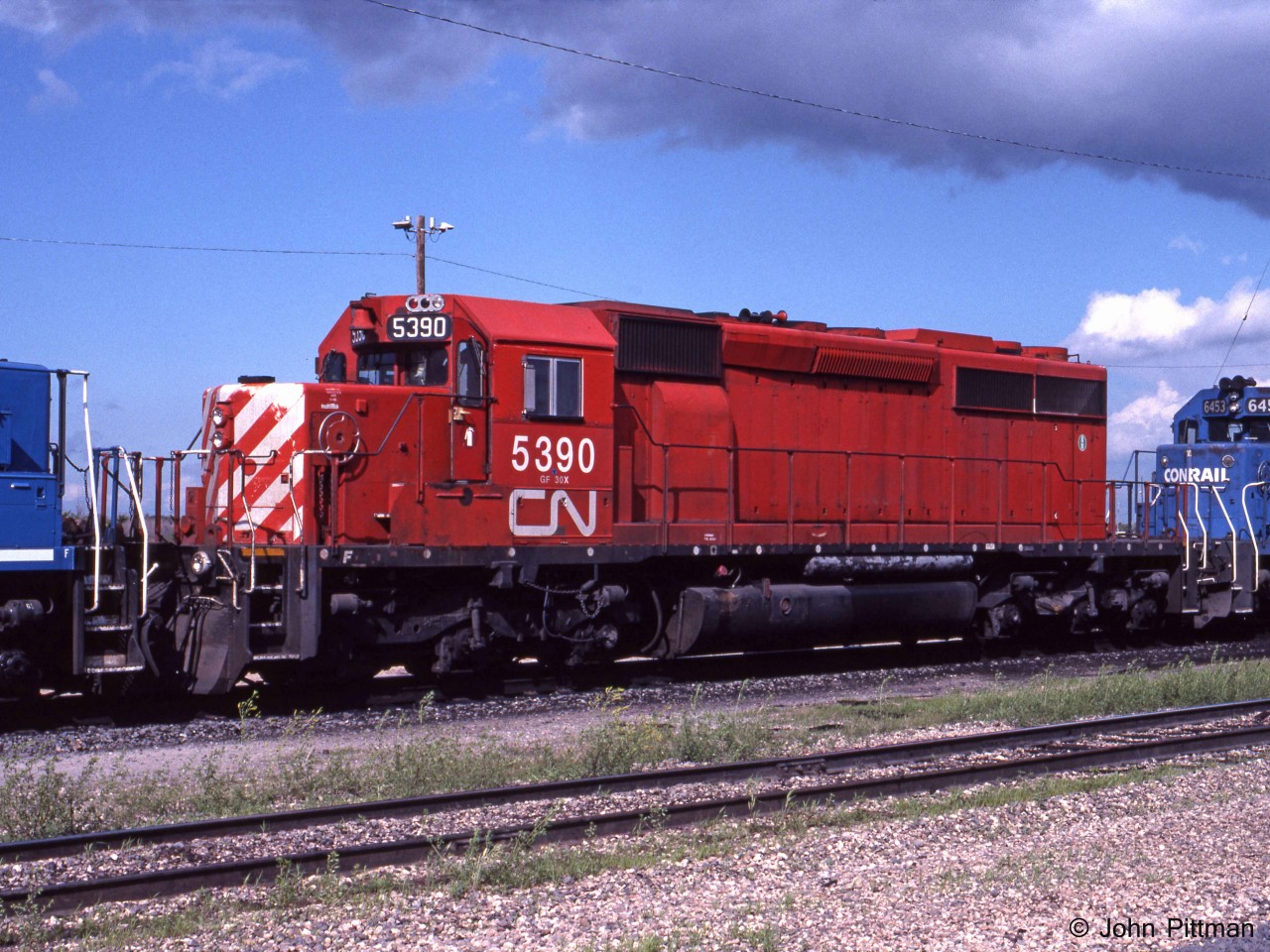 CN 5390, an Ontario Hydro owned SD40-2 formerly assigned to CP Rail, is one of 11 passed to CN along with O.H.'s coal hauling business. My source indicates CN 5390 was formerly CP 5781. Traces of a multimark can be seen around the radiator intake grilles. 
It is resting outside the Symington Yard Diesel Shop in eastern Winnipeg, sandwiched between Conrail units CR 6662 and CR 6453. It could be used on any train systemwide. CP re-acquired 10 of them in year 2000. 
For a while after privatization, it was sometimes still possible to obtain permission to visit CN facilities and take photographs. Sincere thanks to the people who authorized me, I hope there were no downsides for you.
