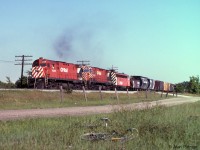 C424's CP 4239 and CP 4211 and an FP7A are working hard pulling a long train of general freight northbound on the Mactier sub. Recently re-painted CP 4239 has the wide stripe multimark scheme, as does the FP7A. CP 4211 wears the original narrow stripe multimark scheme it received some years before.<br>
The train is on the main line with Elder siding between it and the photographer. <br>
Interesting flatcar loads on this train included a combine harvester and a large transformer.<br><br>
Our mode of transport was hastily abandoned in the grass when my brother and I heard this train coming. We were only expecting to see "The Canadian".<br><br>
Since 1991 the south lead to CP's Vaughan Intermodal Terminal branches off Elder siding right about here.
