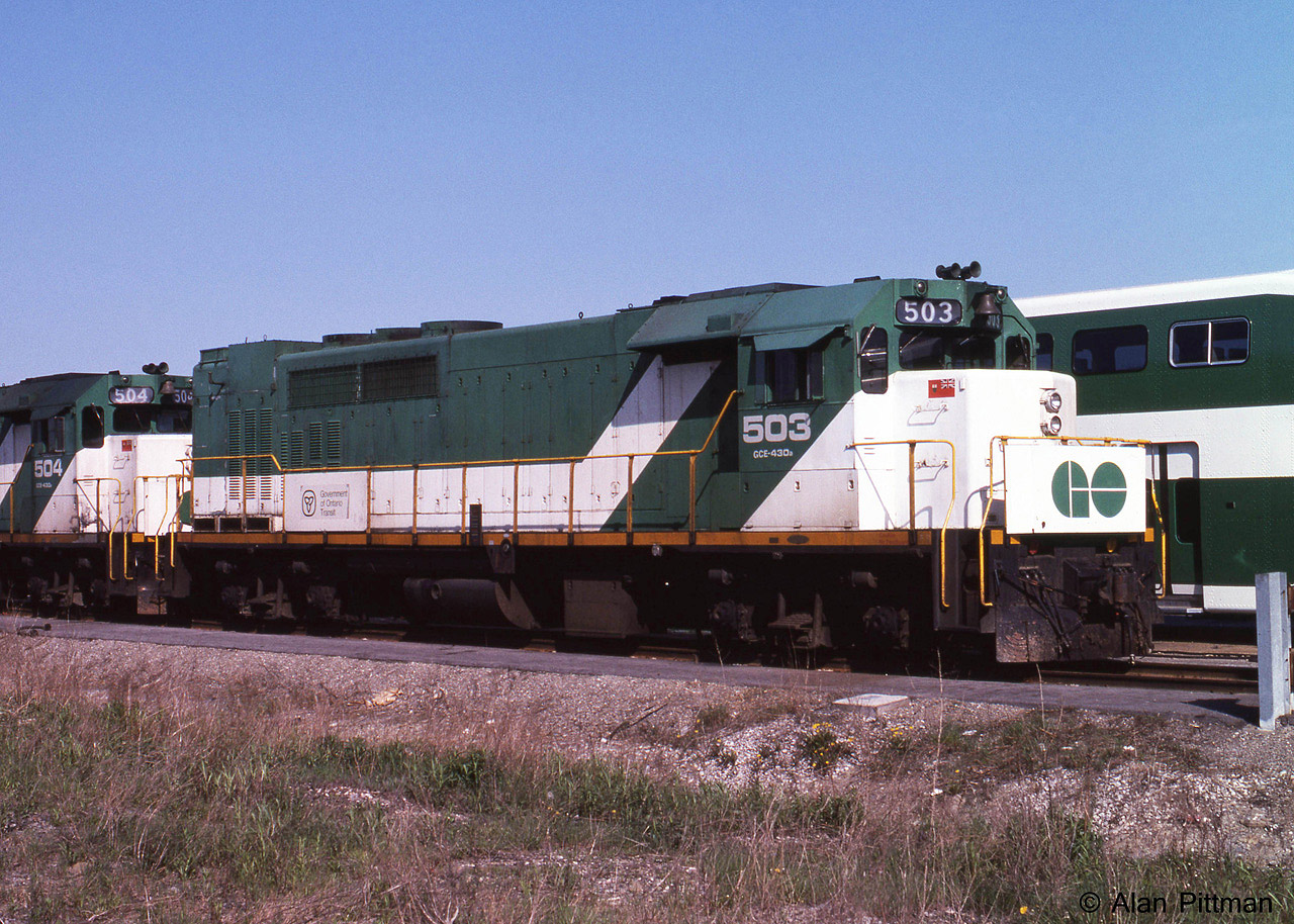 GP40TC GOT 503 and 504 are sitting out the weekend in GO Transit's Willowbrook Yard, at the time maintained by CN. One of the original batch of locomotives purchased for GO Transit, it had previously been CN 603, GO 603, and GO 9803, before adopting GO's long-term green and white colour scheme and its final GO Transit unit number 503. Some of GO's original bi-level coaches can be seen the next track over, first deliveries began in 1977. 
The GP40TC (TC = Toronto Commuter) was unique to GO transit, being more or less a GP40 built on an SD40 frame. The nose is shorter and the long hood extended to provide space for an auxilliary power diesel generator set. The fuel tank occupies a fraction of the space between the trucks. 
GO Transit's GP40TC fleet 500-507 were sold to Amtrak in 1988, renumbered 192-199 and modified for Amtrak's purposes.  They were renumbered AMTK 520-527, and got de-turboed. Some remain active in 2015 for work trains etc, having outlasted Amtrak's F40PH locomotive fleet.