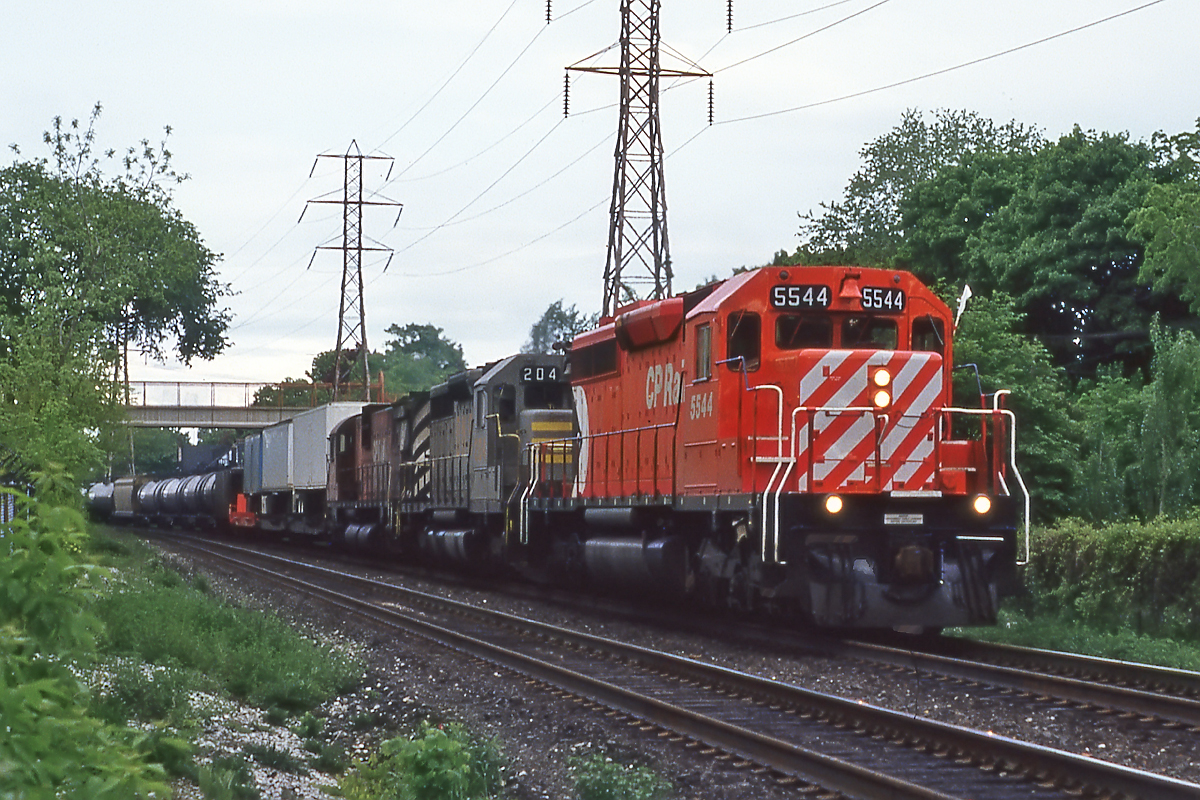 In fresh paint, trailing a QNSL SD40 that will soon become CP's, and an M630 rolling westbound at Mount Pleasant.
