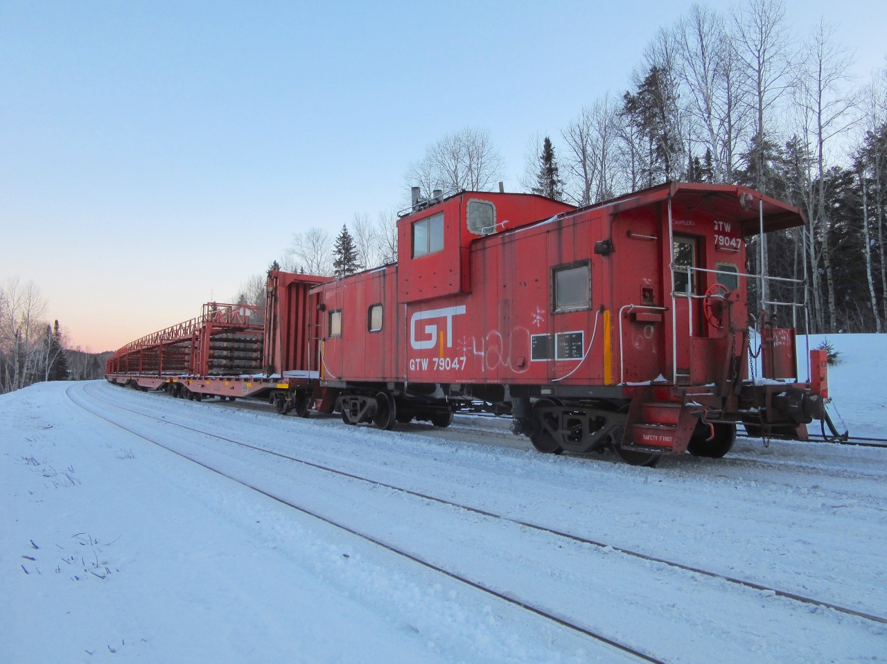 As the sun sets, temperatures approach the -35 degrees celsius mark. Work 909 is in the siding at Thorlake to let 102 by while the brakeman has a fire going in the GTW caboose.