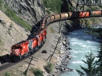 A westbound grain train passes under the now-removed Trans Canada Highway bridge just east of Glenogle Siding. Since this time a new alignment of the TCH takes traffic over a very high bridge over this part of Kicking Horse Canyon.