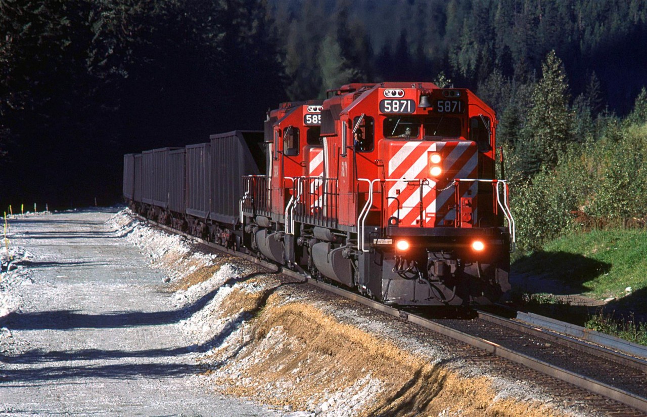 My note call this Flat Creek. This is where the new MacDonald Tunnel will emmerge on the west side of Rogers Pass. The construction of new track bed is evident to the left.
Coal empties are working up hill.