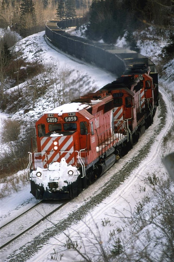 When I first showed a picture from this vantage point in public (at the AltaMont rail gathering in Montana), folks that were familiar with the area could not believe that this was in Calgary. It is one of my favorite locations.
This westbound sulphur train rumbles through the S curve just east of Brickburn Siding. About 2/3 back will be a robot car and another couple of DS-40's.