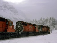 The westbound grain train appears to be diving into the slope that leads down to Field. Cathedral mountain is revealed by a brief split in the clouds.