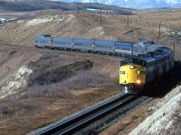 Eastbound "Canadian" approaching the dinky Glenbow siding. There was a small long-abandoned building adjacent to the siding that was close enough to the tracks to suggest that it may have served as a RR structure at one time.
The Rocky Mountains are in the background. At this time, it was quite a walk into this area. Now it is a park with easy bike and car access.