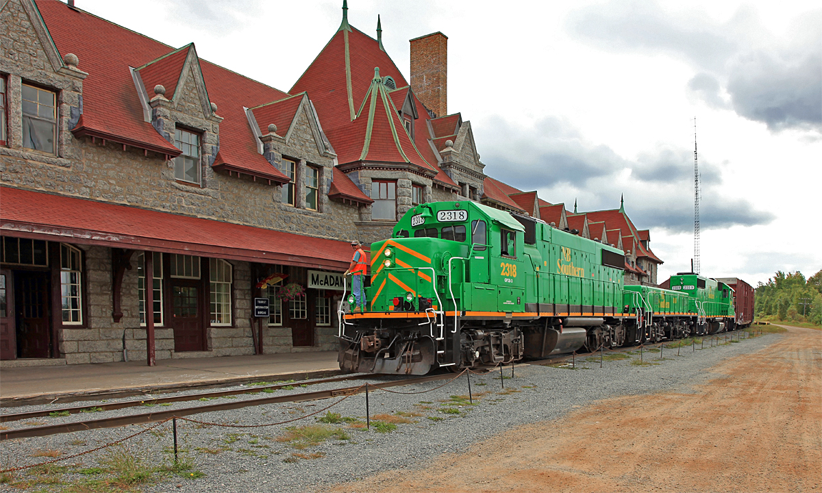 NBSR 908 pulls a cut of cars past the impressive McAdam Station to drop in the yard on the far side. After returning the power to the train and a change of crews there will be a wait of over an hour for trackwork ahead to clear up before they can proceed.