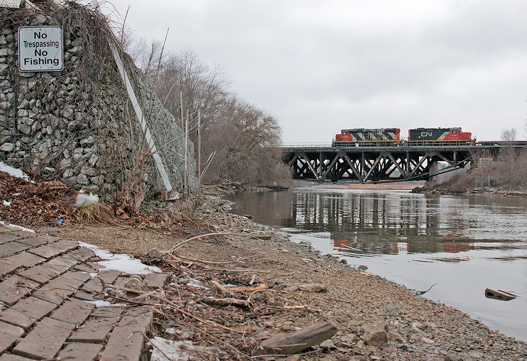 No Fishing, No Trespassing  CN 556 screams past with two idler cars in tow back to Oakville on this cold winters day.