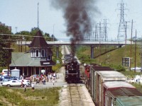 Its a rather eventful Saturday for the fans gathered at the old Grimsby CN station as CN 6060 starts up eastbound as a westward CN freight crawls by. This special oil-fired (converted) locomotive never failed to attract a crowd. That is the Christie St overpass in the background, and I am standing, alone, I might add, on the Maple Av bridge, with most fans content with being at the station. The track in the foreground veers off to the historic GTR station (out of view). The track looks disused in this scene; last time I saw anything on it was a boxcar a few months earlier, probably a bad order car. The track was removed a few years after this image was taken, and the CN station burned down in an electrical fire on the very last day of 1994. Currently a VIA kiosk occumpies this location, yet only Amtrak provides service down thru Niagara any more.