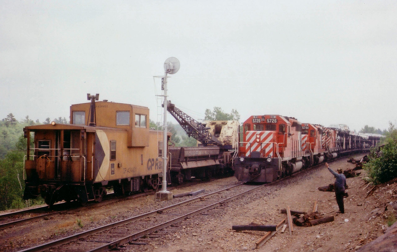 Reasonable entertainment on a crappy (but warm) dull day; seemingly a specialty of mine :o) this time out driving around featured a stop at Pointe au Baril to see 'if anything was happening'. CP 7090 was there; crane & van. Since I had brought the girlfriend along; the rail worker decided he could pass some time showing the little lady how things worked while they waited out a northbound freight. He then proceeded to operate the equipment; moving the bucket around, etc., and keeping her entertained while I watched in amusement. After about 20 minutes it was train time. Too bad it was so lacklustre a day out there; but the scene with CP 5726, 5744 and 4725 was well worth the wait.