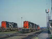 This was an unusual movement. A pair of RS-18s came into Rockingham Yard with a train and then headed west van hop. It was very unusual to see a pair of RS-18s on the road in the Halifax area at this time. 

CN 3624 was wearing a variation of the noodle paint scheme that a few RS-18s and RSC-14s wore - a yellow frame stripe replacing the white (gray) stripe that was standard with that scheme. 

CN 1779 sitting to the left would have been switching Rockingham on day shift and is now idling by the scale house. 