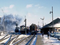 <b>Down at the Depot</b>: It's a busy scene at the Canadian Pacific station in Galt Ontario, at 13:15 on a cold February day in 1958. Train 38 is on the station track, the rear car of which is visible. On the next track over, a westbound freight is about to leave behind an FA1 leader and RS unit trailing. The steam locomotive in the background is CPR 2-8-2 5135, waiting for repairs. On the far left is overhead catenary for CP subsidiary Grand River Railway's electric operations. Beside the station, a CP Transport Twin Coach bus is waiting for passengers going to Preston and Kitchener.  Today the steam, first generation diesels, passenger trains, electric motors and buses are gone, but the station remains - still in use by the CPR!