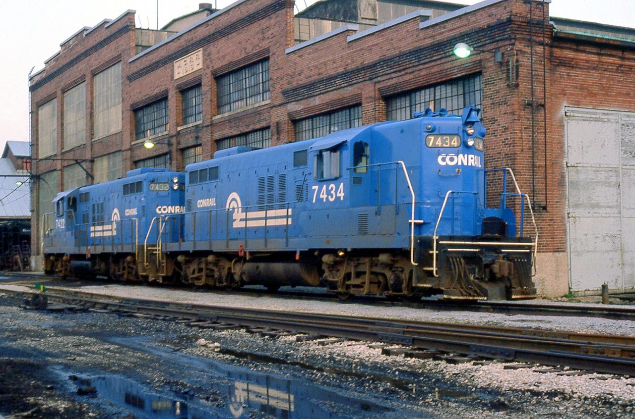 Conrail GMD-built GP9's 7434 and 7432 (originally of NYC heritage) sit out in front of the former Michigan Central Railroad shops in St. Thomas, Ontario. The shops' MCRR logo is visible just above the pair of blue Geeps.