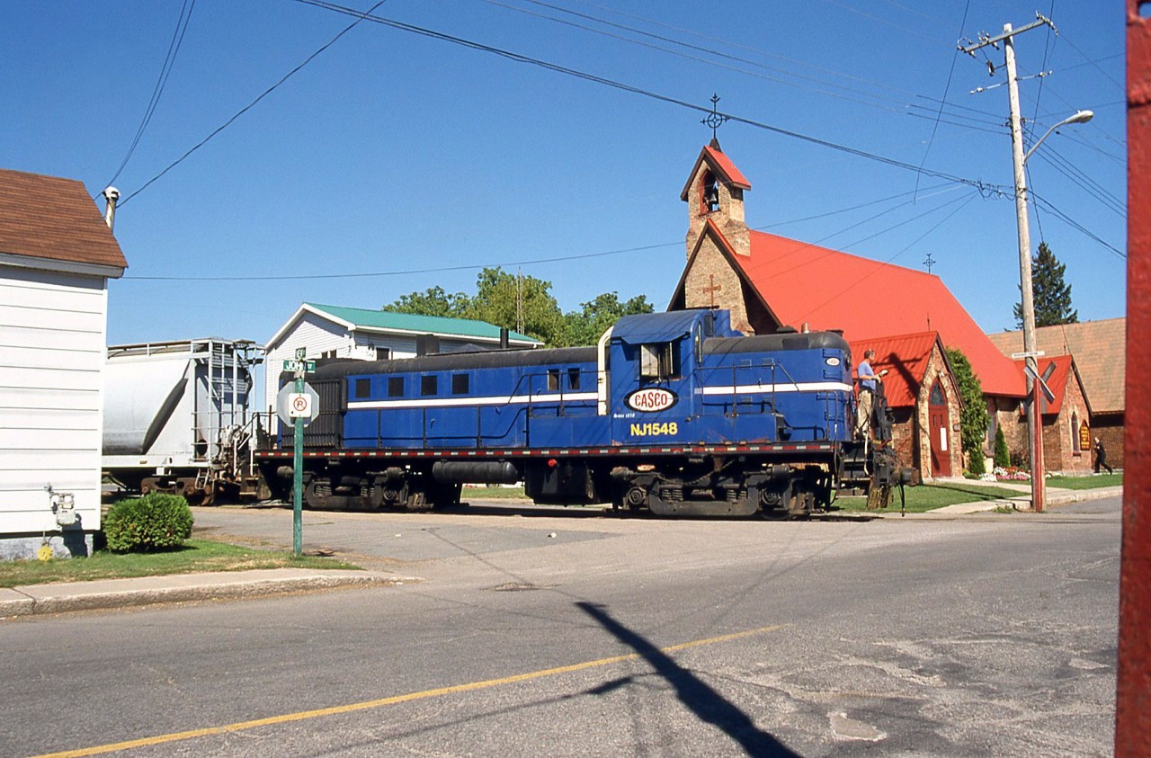 Another view of Canada Starch Company (CASCO)'s oddball Alco RS3m switcher, NJ 1548, crossing John St. by St. Paul's Church in Cardinal ON. Built as a Central New Jersey unit of the same number, it received a 1200hp EMD 567 repowering by Conrail, but at some point had its hood rebuilt back to a more conventional Alco appearance (still retaining the EMD engine). It has since been scrapped and other switchers take care of duties at the Ingredion plant, threatened by closure.