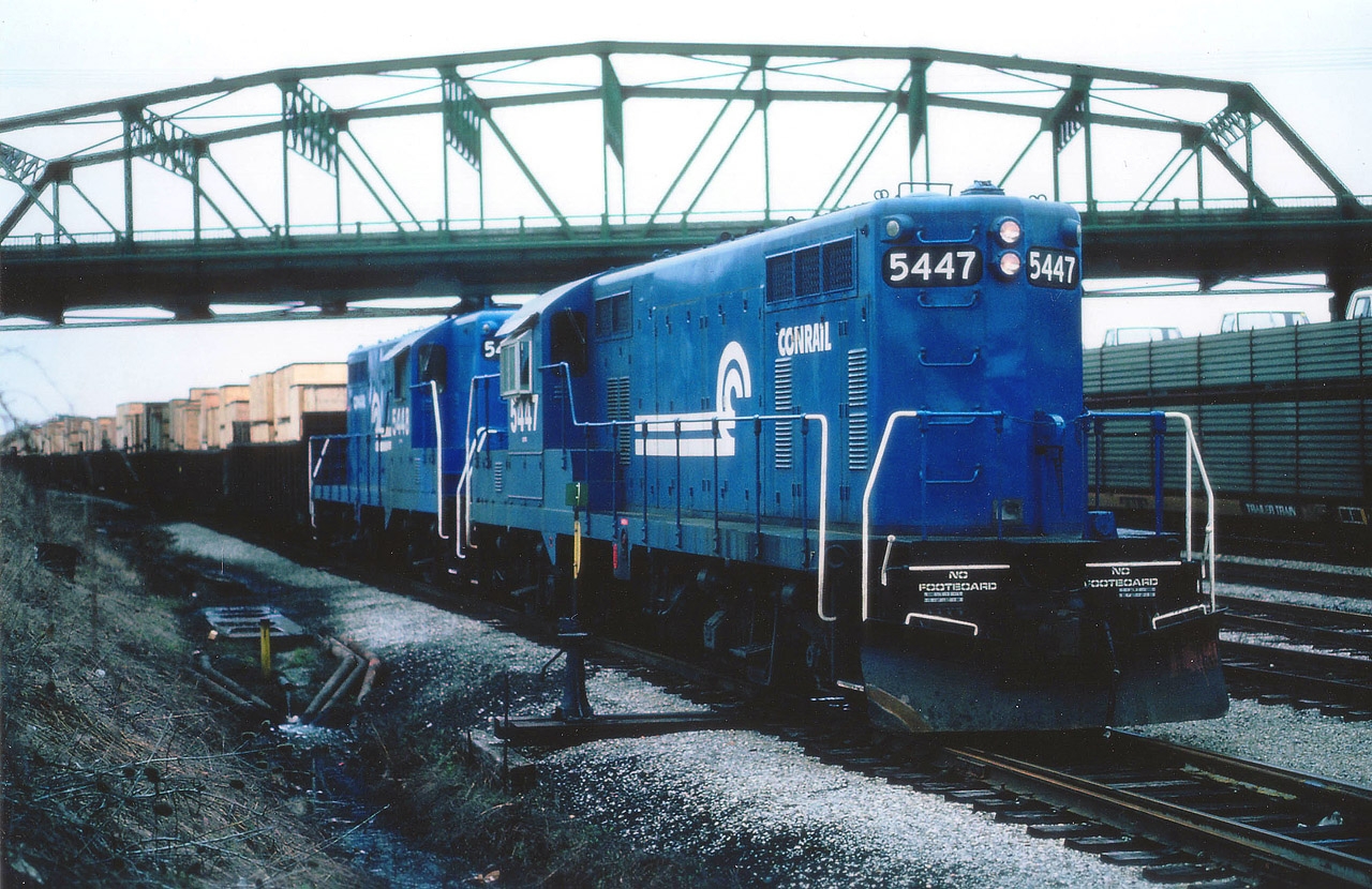 Seen on Fort Erie trackage now long removed, Conrail GPs 5447 and 5448; both fresh from a rebuild program that ran from 1976-1979 either by ICG, ROCK or MK; haul a long string of container laden gons off the old Dunnville Sub trackage heading toward the USA. Overhead is the Central Ave roadbridge. Some minor changes resulted in these units being reclassified as GP8 rather than the GP7s as originally built. Would be nice if some experienced railroader with this group could verify what sort of merchandise was shipped via this Fort Erie "Container Train". I have always been curious.