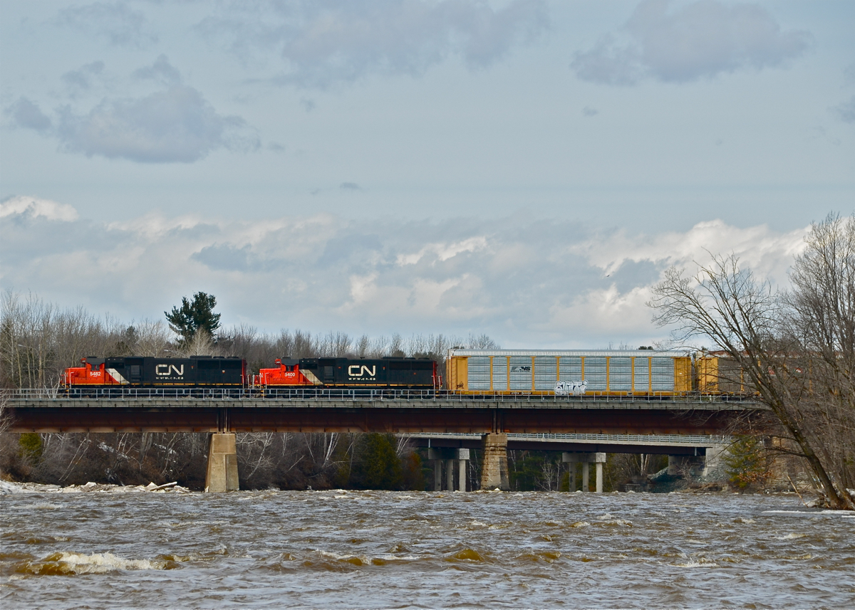 A pair of ex-Oakway SD60's (CN 5482 and CN 5400) leads CN 401 through Daveluyville as it passes over the raging Bécancour River.