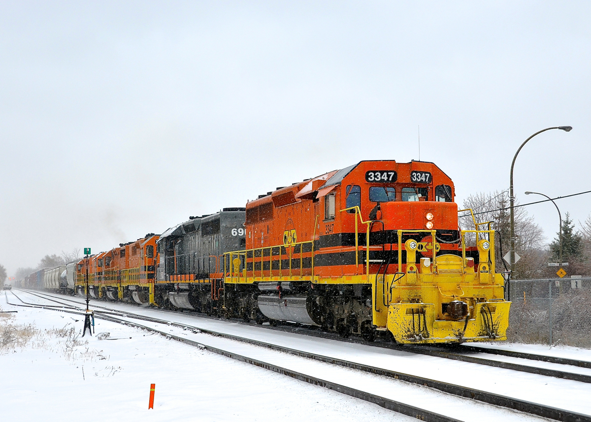 Lots of orange power on a snowy day (finally). During Montreal's first significant snowfall this winter, a very long Quebec Gatineau transfer from CP's St-Luc Yard to QG's Sainte-Thérèse Yard is eastbound on CP's Adirondack sub with 6 units and 7,100 feet of train. Full lashup is QG 3347, QG 6904, QG 2300, QG 2501, QG 801 & QG 3801.