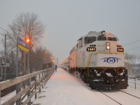 <b>White unit in the snow.</b> AMT 84 with white ex-GO Transit AMT 1341 leading is arriving at Lasalle station as the snow falls.