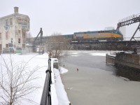 <b>Snow and ice.</b> VIA 903 leads VIA 55 over the icey Lachine Canal as the snow falls on a stormy day. At left is the Wellington Tower.