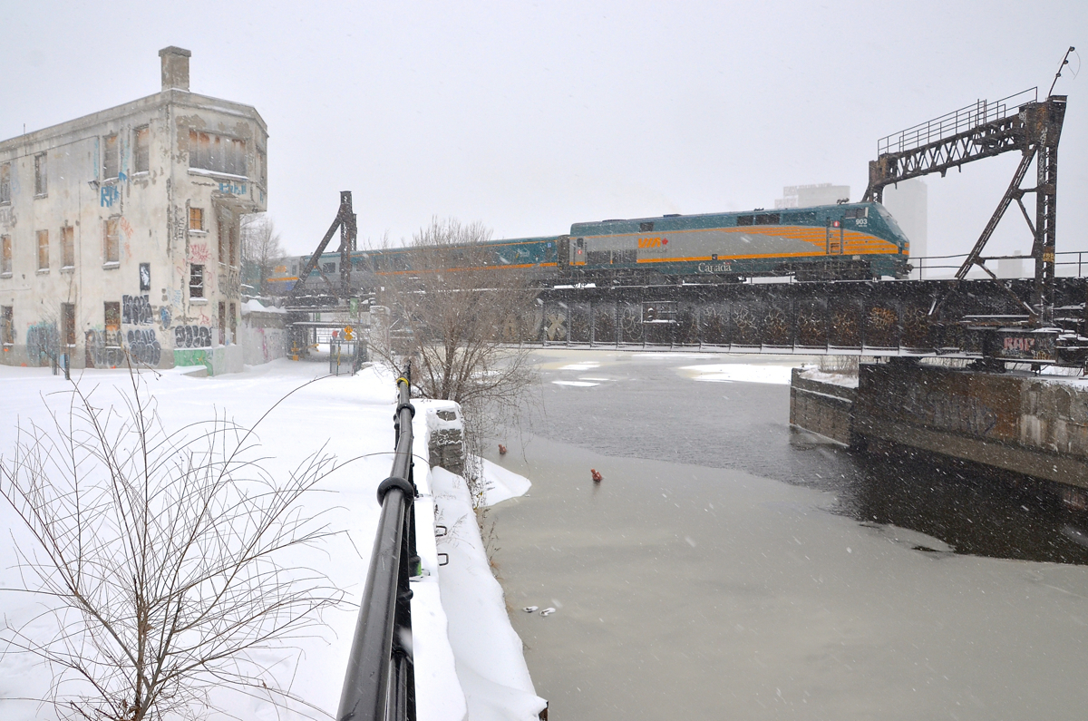 Snow and ice. VIA 903 leads VIA 55 over the icey Lachine Canal as the snow falls on a stormy day. At left is the Wellington Tower.